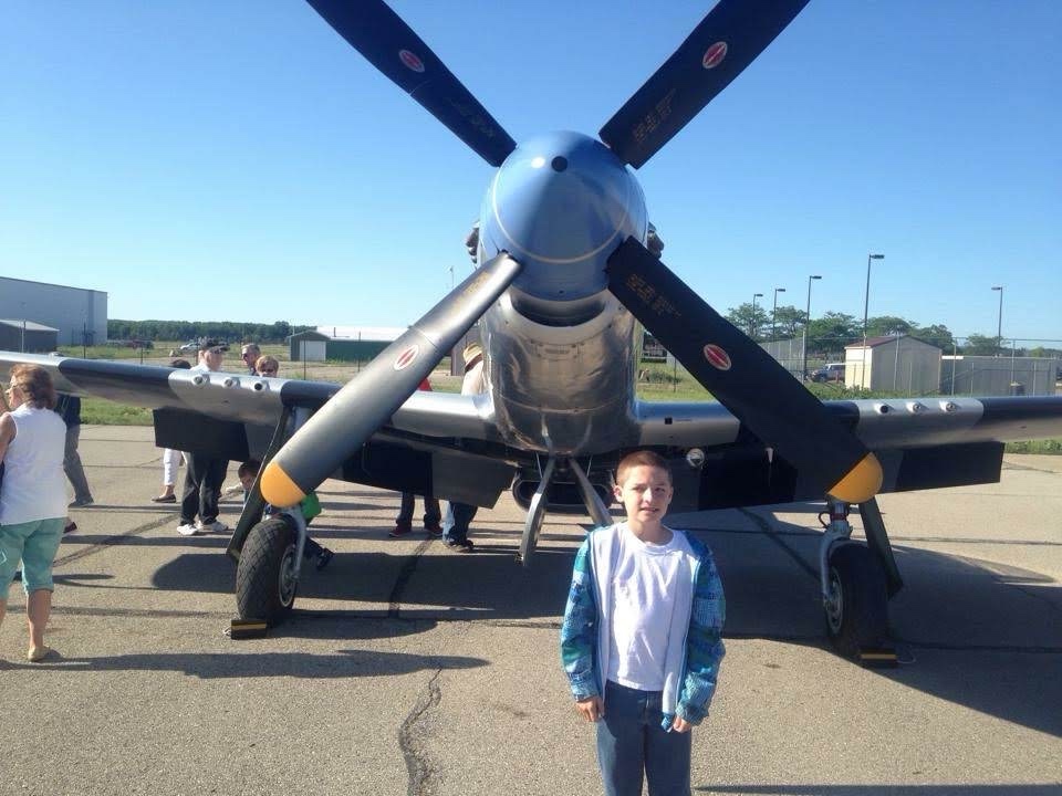 Charlie as a child in front of a warbird